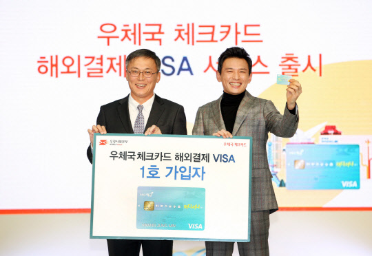 우정사업본부는 5일 인천국제공항 1층에서 전 세계 VISA가맹점에서 우체국체크카드를 사용할 수 있는 '우체국 체크카드 해외결제서비스'를 출시했다. 강성주 우정사업본부장(왼쪽)과 우체국해외체크카드 1호 가입자인 우체국금융모델 탤런트 황정민씨가 기념촬영을 하고있다. <우정사업본부 제공>